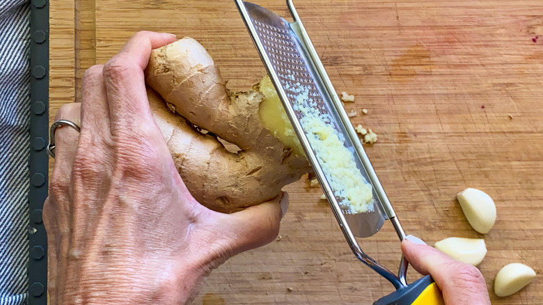 grating ginger on cutting board 