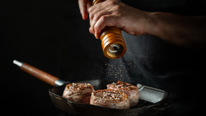 person peppering a steak