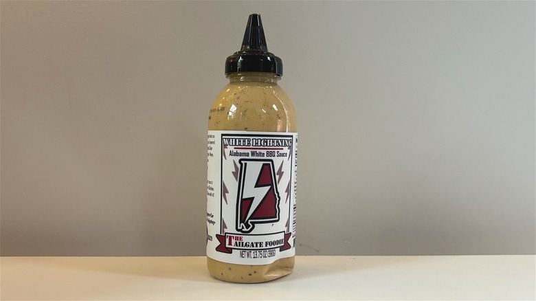 Bottle of The Tailgate Foodie White Lightning BBQ Sauce on white table