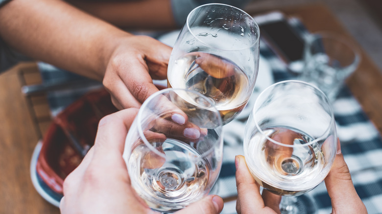 people clinking white wine glasses