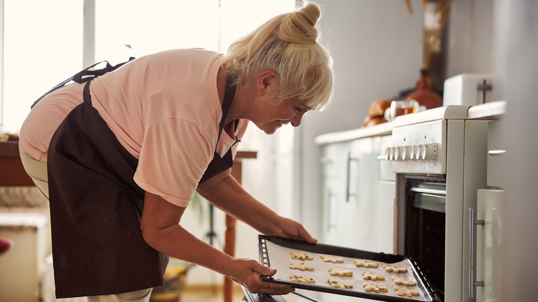 Woman putting cookies in the oven