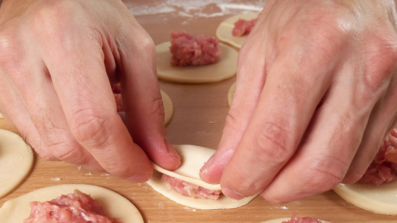 Hands folding a dumpling