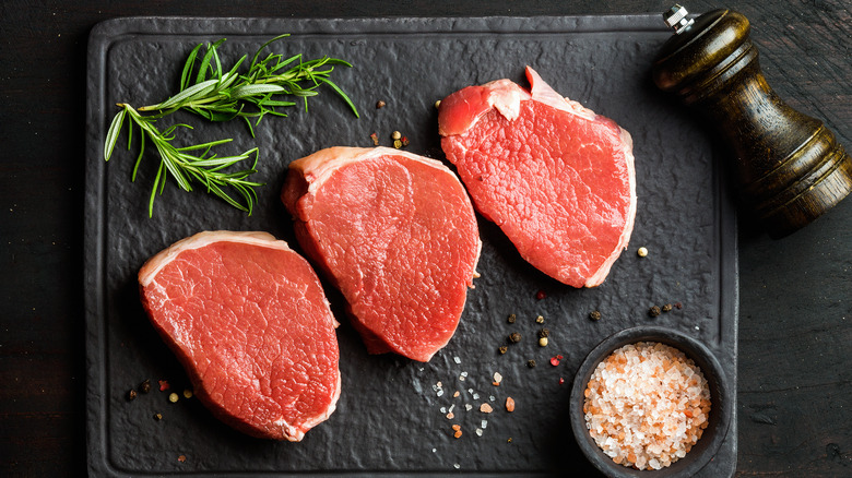 Three raw round steaks.