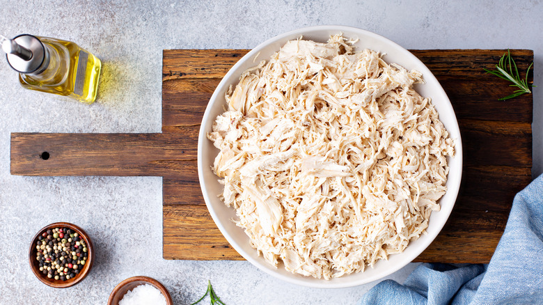 Shredded chicken in white bowl with oil