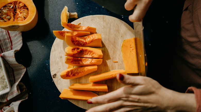 Person chopping up butternut squash on table
