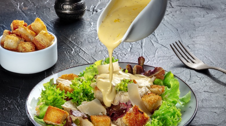 Caesar dressing being poured on a salad