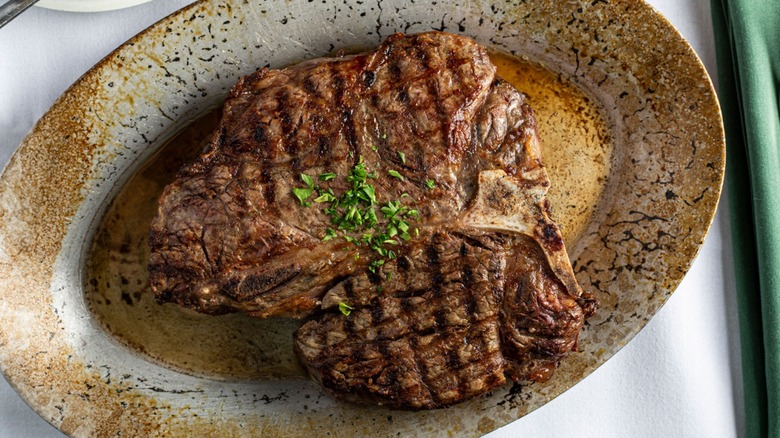 T-bone steak on sizzle plate topped with herbs