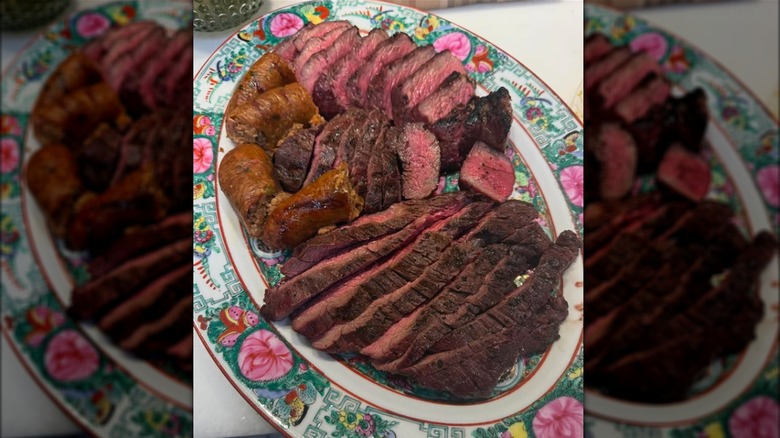 Slices of steak and sausage on colorful plate