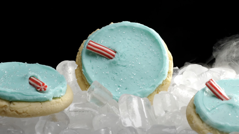 3 Vanilla cookies with blue frosting and red and white edible straws on top of ice