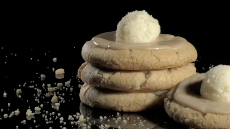 3 brown pancake cookies with brown maple frosting and a dollop of buttercream frosting on top