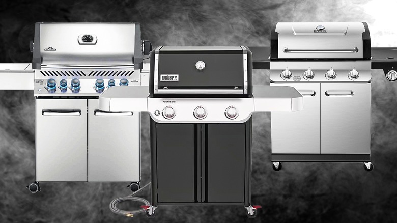 Two stainless steel gas grills on either side of a black one.