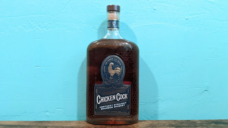 Chicken Cock bottle on wooden table in front of blue wall