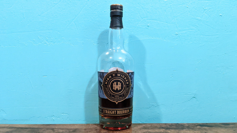 High & Wicked High-Rye Straight Bourbon bottle on wooden table in front of blue wall