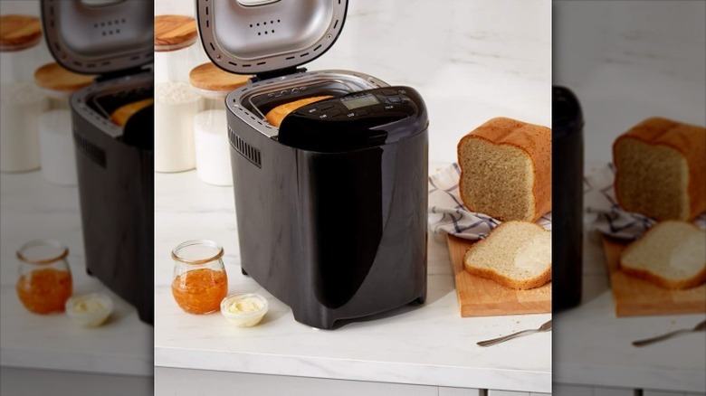 Amazon Basics bread maker in black on counter next to fresh baked bread loaf