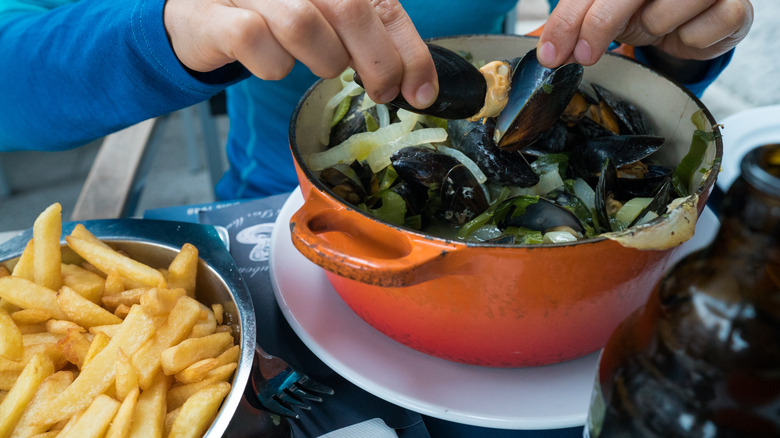 Person digging into moules frites