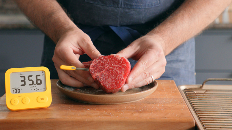 man holding small roast with Combustion wireless thermometer inserted and Wi-Fi display alongside