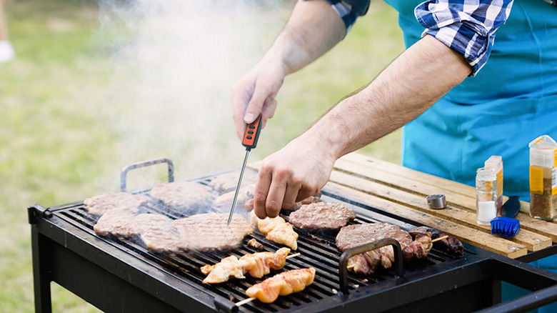 Man testing steaks on grill with ThermPro instant-read thermometer