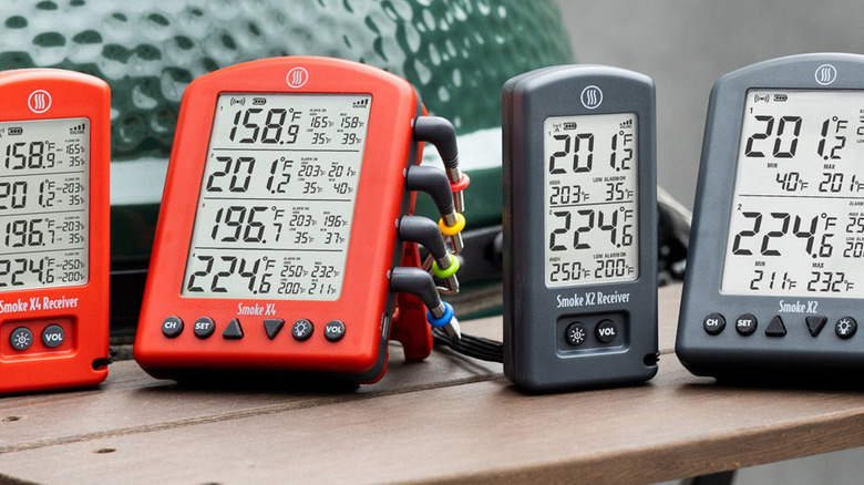 ThermoWorks smoke thermometers in two colors on the side table of a Big Green Egg grill/smoker