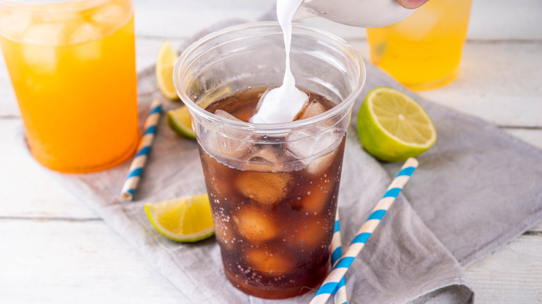 Soda with creamer in plastic cups surrounded by lemon, lime, and straws