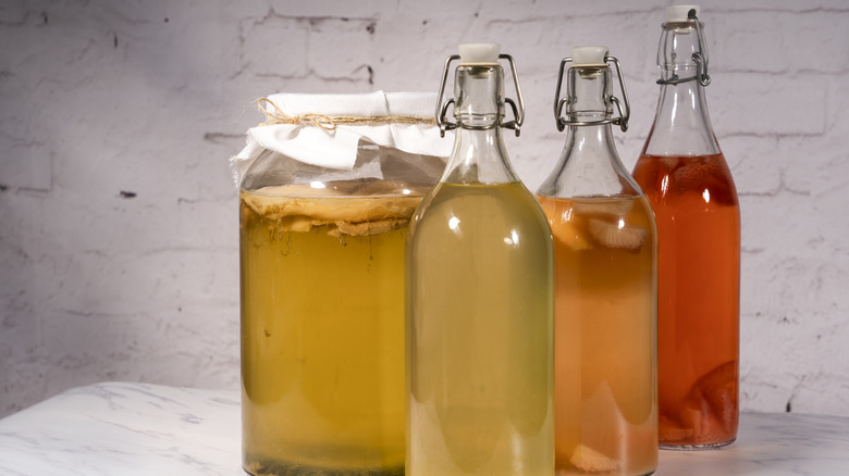 Kombucha in bottles and a jar on a countertop