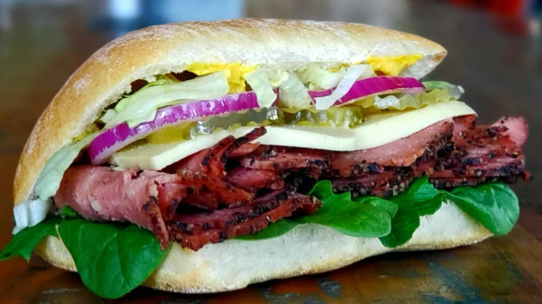 NoButcher's plant-based Pastrami sandwich with Swiss vegan cheese, greens, red onion and sweet maple-mustard aioli