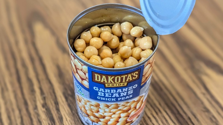 Top view of open can of chickpeas on wood background