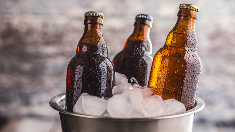 Three brown glass bottles in a bucket of ice