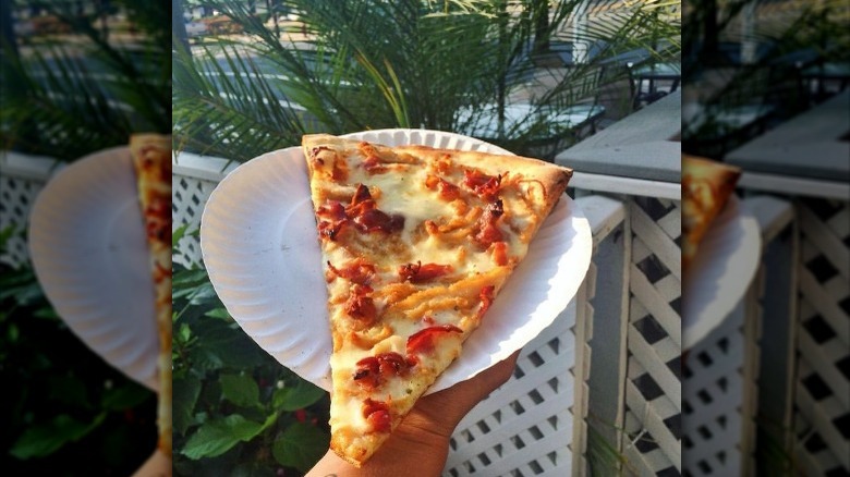 holding pizza slice on plate