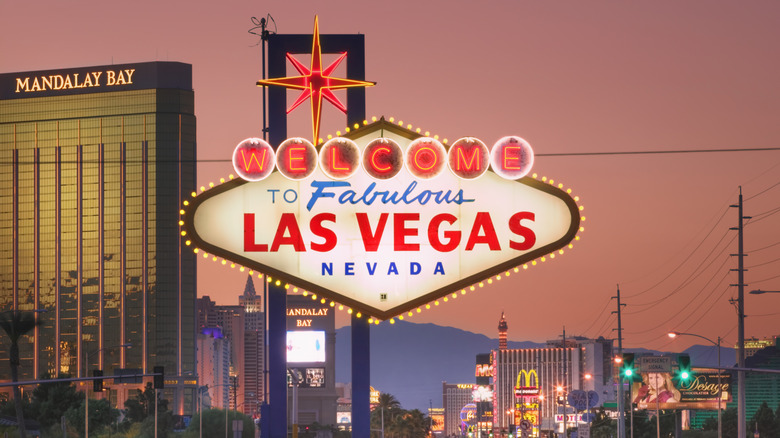 Sign reading "Welcome to Fabulous Las Vegas Nevada" pictured against city backdrop at sunset