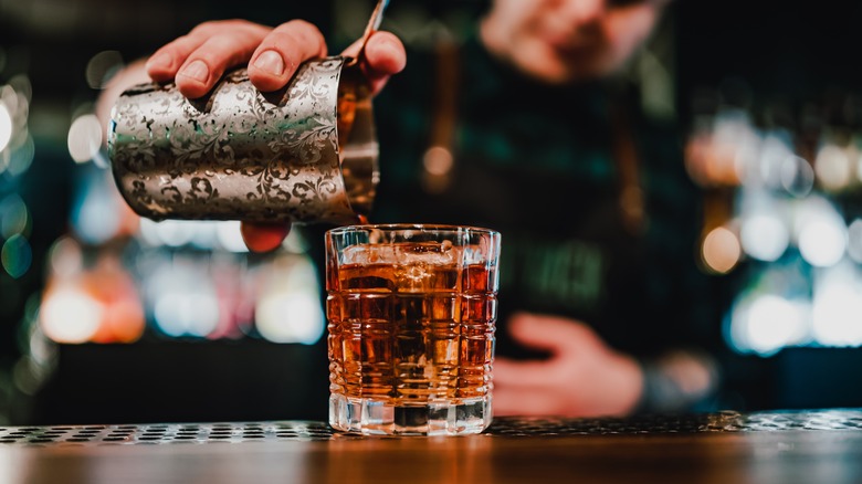 Bartender pouring Negroni into glass