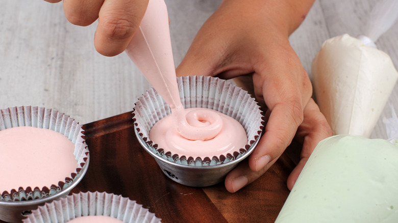 Person piping into muffin cups