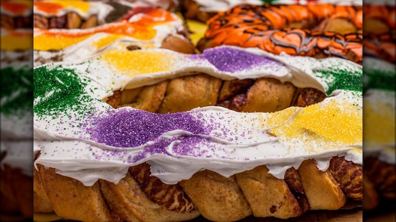 Braided cinnamon pastry topped with white icing and mardi gras colors