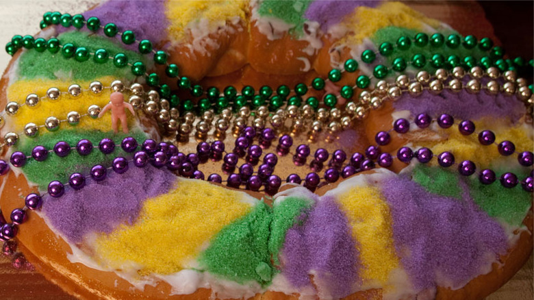 Brown puff pastry topped with gold, green, and purple icing and beads