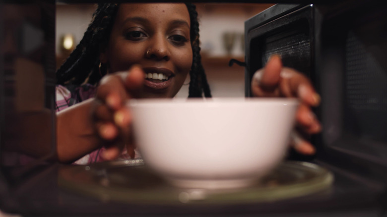 Person putting bowl in microwave