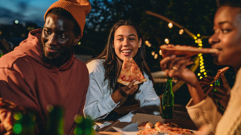 Friends eating pizza at night