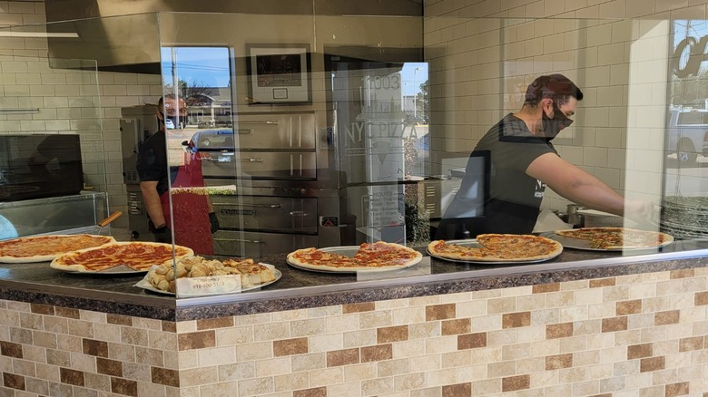 Two employees at pizzeria counter