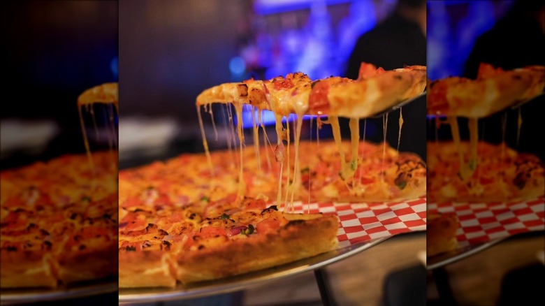 Cheesy pizza being plated