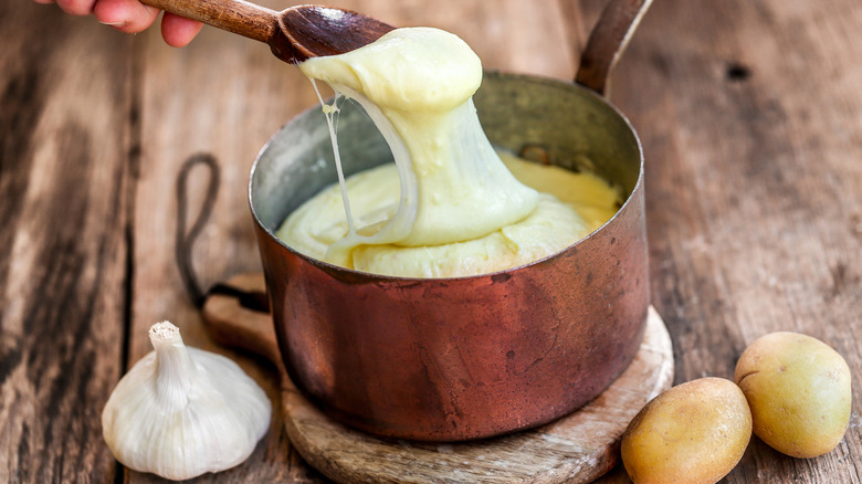 Person dipping spoon in aligot