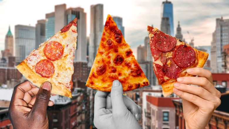 hands holding pizza slices skyline