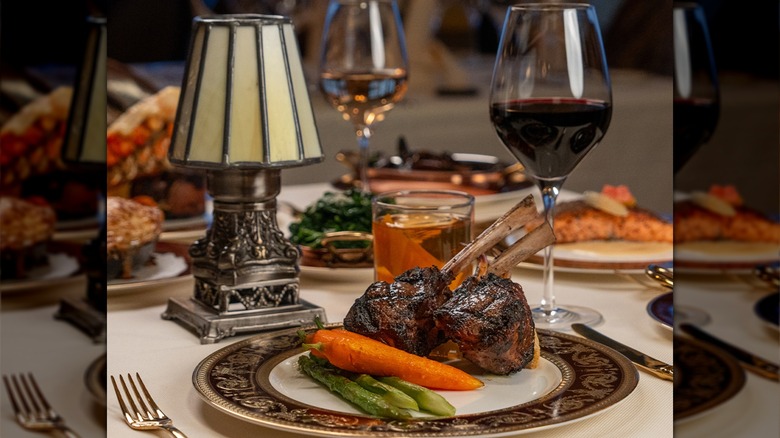 Bohanan's lamb chops, carrots, and asparagus on plate with glass of wine on white table