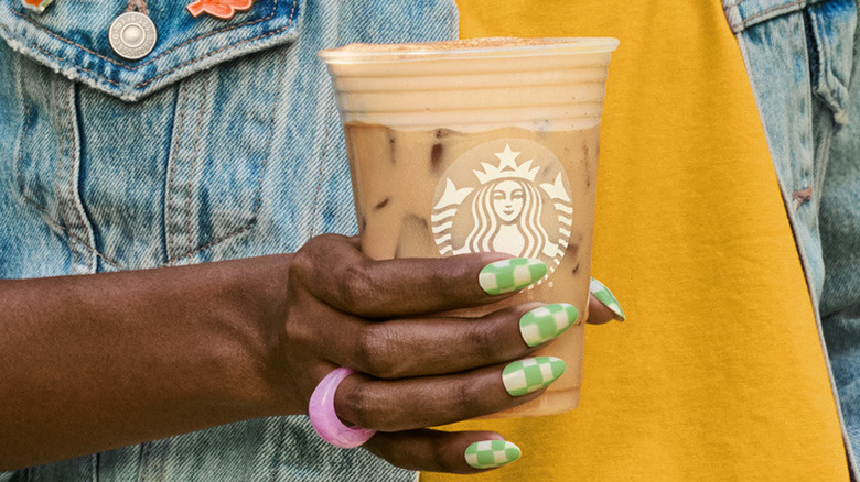 Manicured hand holding iced chai latte