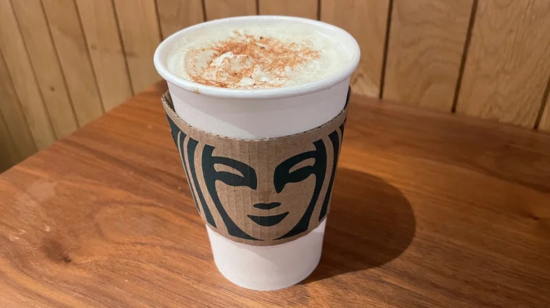 caramel apple spice starbucks drink in a paper cup on a wooden table