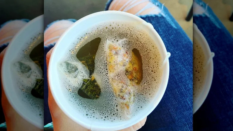 a person holding honey citrus mint tea in a cup top view