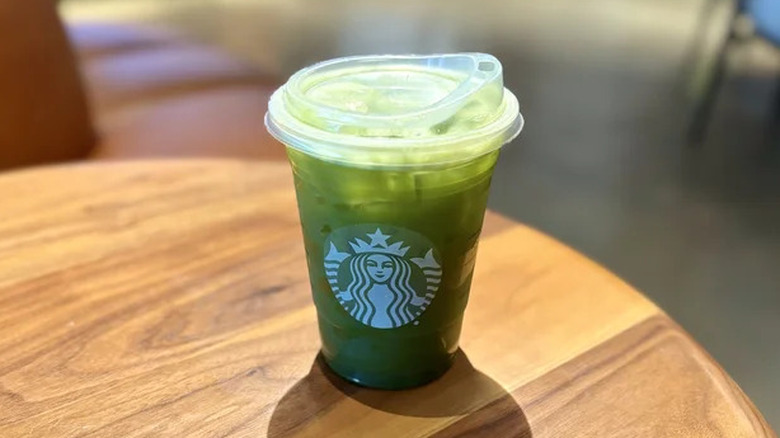 iced matcha lemonade in a plastic Starbucks cup on a wooden table