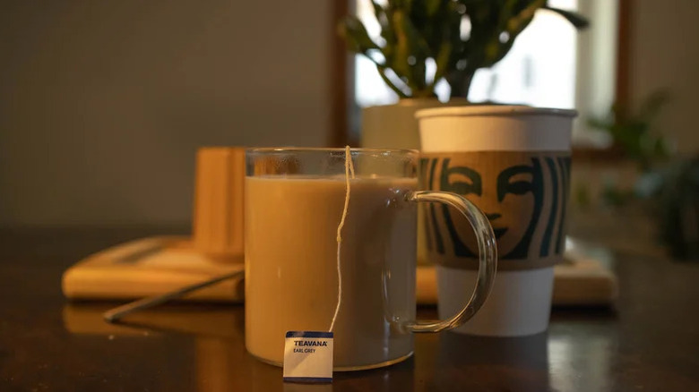 london fog latte in a glass mug next to a Starbucks paper cup