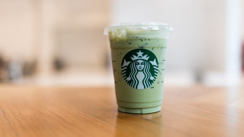 iced matcha green tea latte in a plastic Starbucks cup on wood table