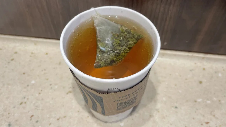 mint majesty tea bag in a paper cup on a beige and brown counter