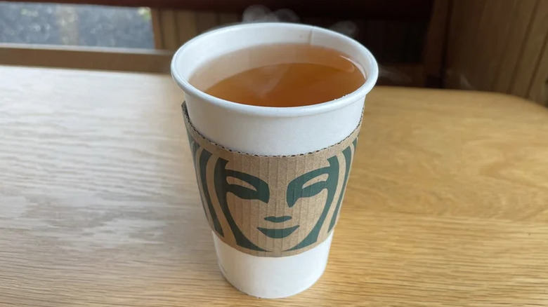 steamed apple juice in starbucks cup on a wooden counter