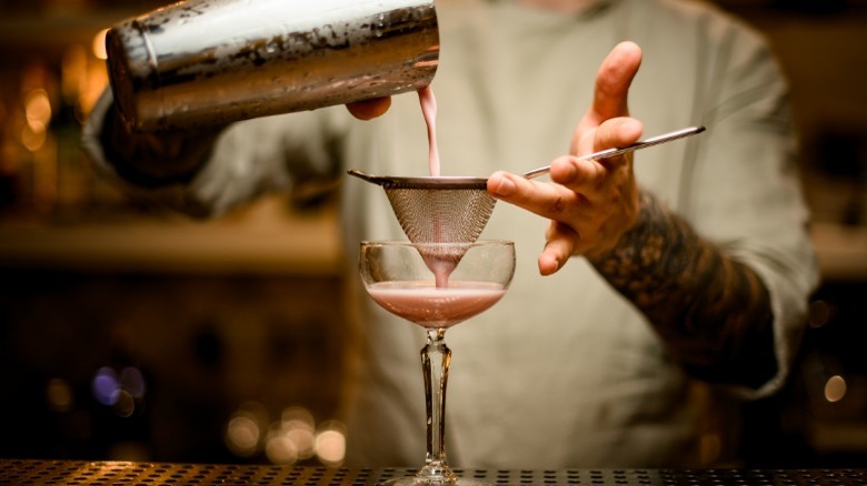 Person straining a cocktail