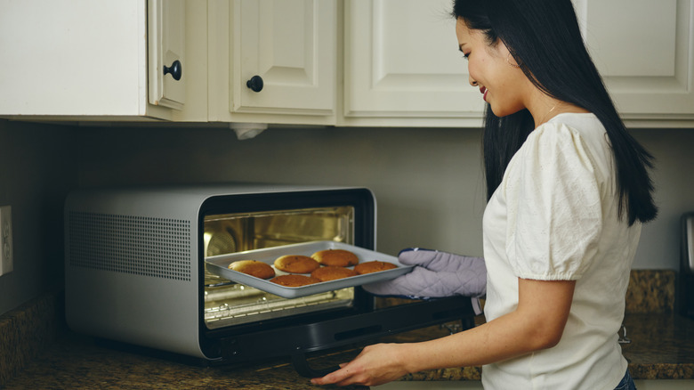 Woman taking cookies out of countertop toaster oven